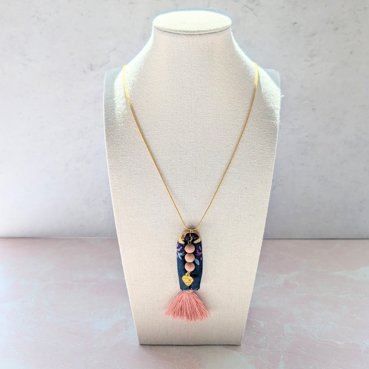 Necklace with a tassel pendant on a mannequin bust against a light background