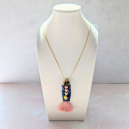 Necklace with a tassel pendant on a mannequin bust against a light background
