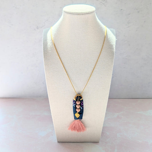 Necklace with a tassel pendant on a mannequin bust against a light background