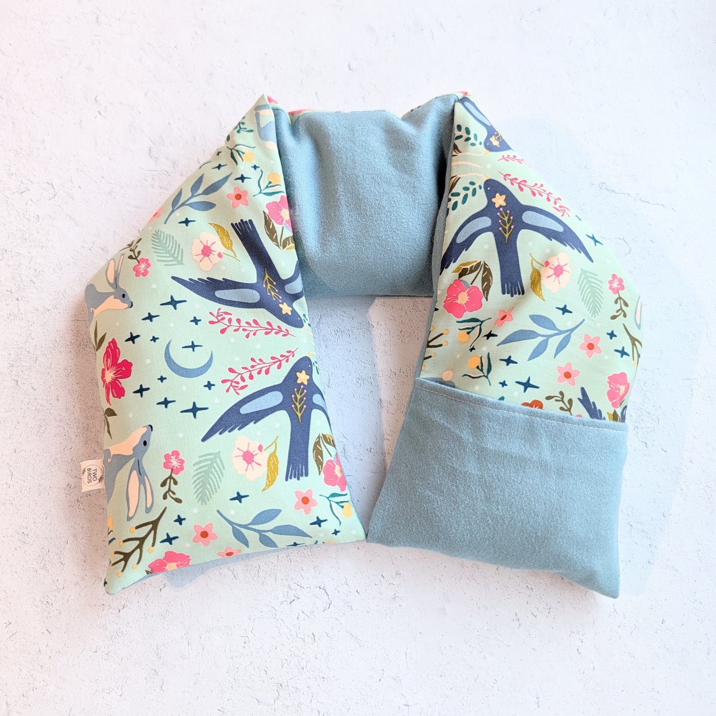 Neck pillow with floral and bird pattern on a light background